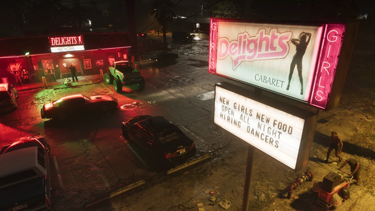 The outside parking lot of a club in Port Gellhorn at night with signs lit up advertising the cabaret. Several cars are parked, a few people linger outside of the club, and two people walk under the sign, one pushing a shopping cart. The outside parking lot of a club in Port Gellhorn at night with signs lit up advertising the cabaret. Several cars are parked, a few people linger outside of the club, and two people walk under the sign, one pushing a shopping cart.